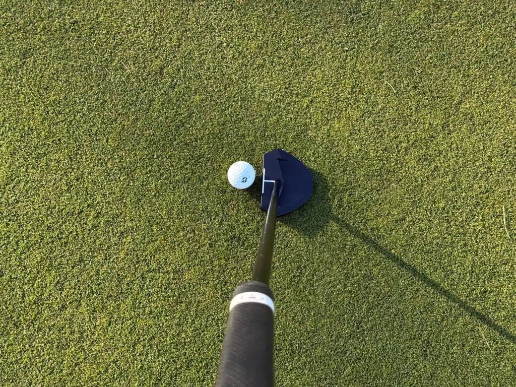 Putting with the OZ.1 on a green, looking down at the putter head and ball