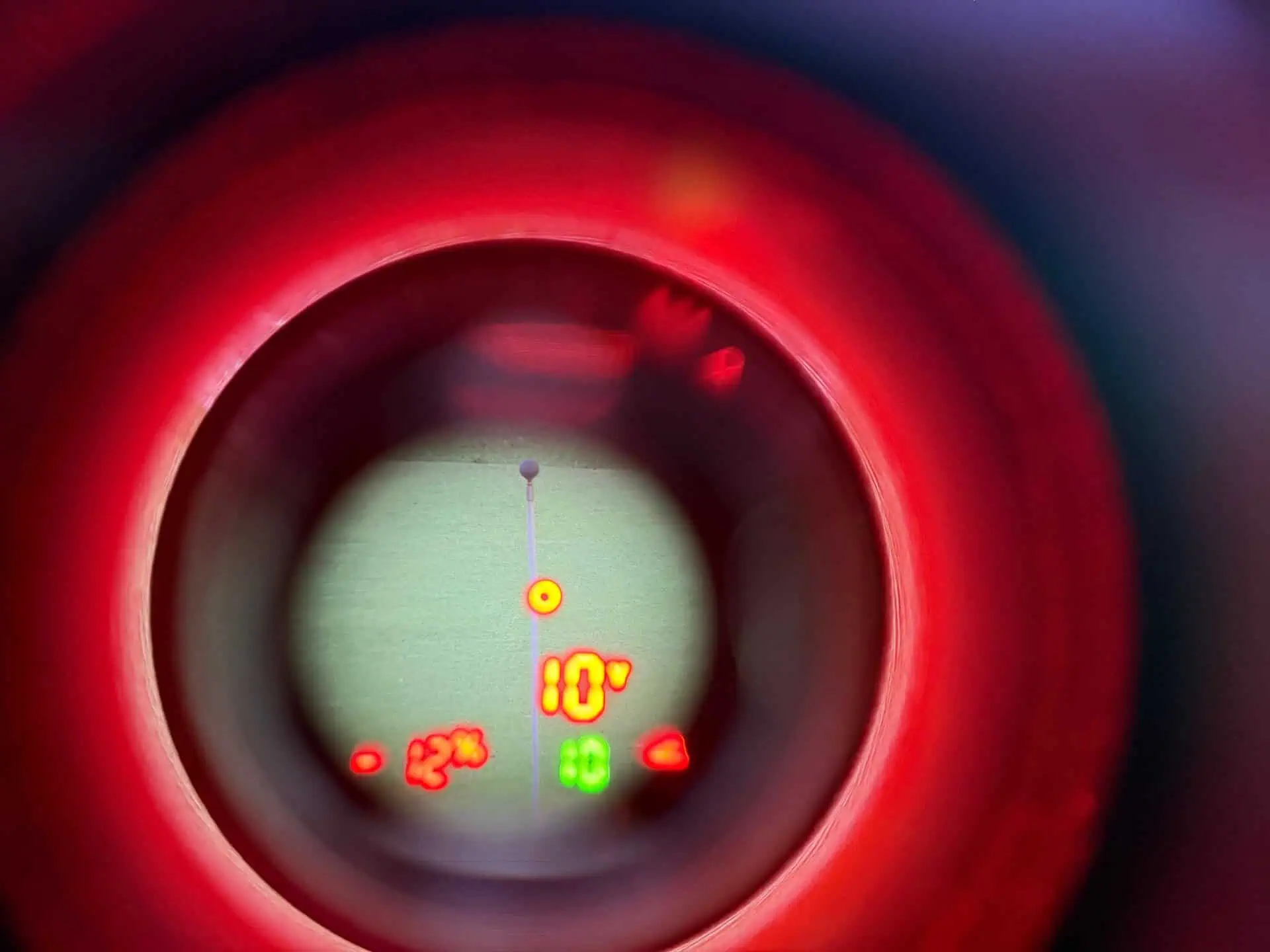 View through the Tour V7 Shift eyepiece showing a red yardage, a green slope yardage and the red Visual JOLT ring